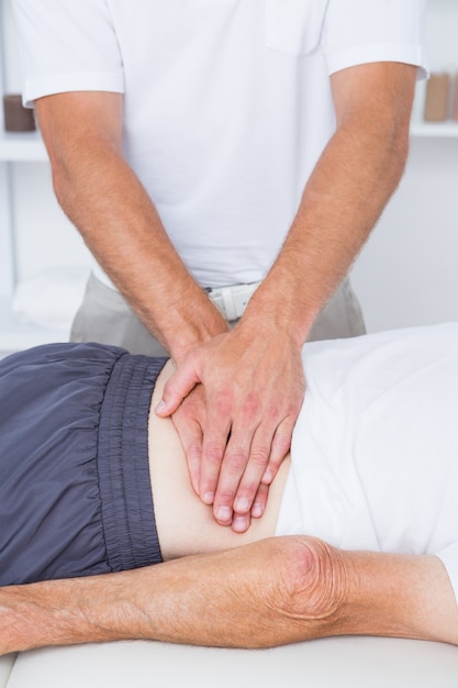 Foto fisioterapeuta fazendo massagem nas costas para o paciente