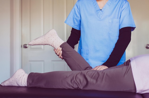 Fisioterapeuta fazendo tratamento para paciente idosa no hospital, dor nas pernas de mulheres idosas, conceito de fisioterapia