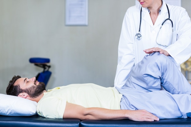 Fisioterapeuta femenina dando masaje de rodilla al paciente masculino