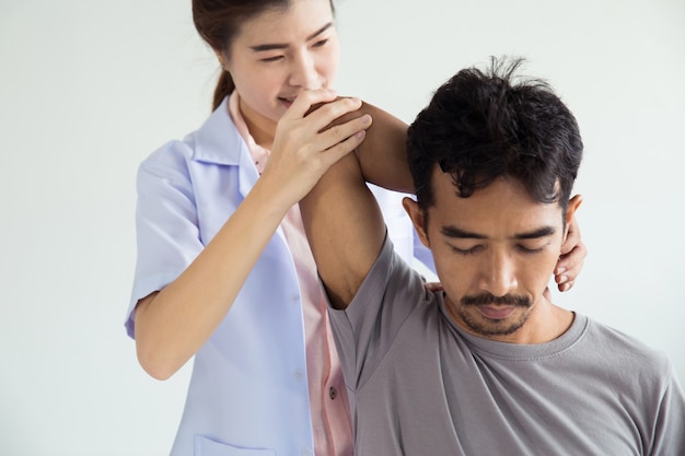 Fisioterapeuta femenina profesional dando masaje de hombro al hombre.