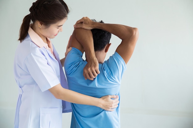 Fisioterapeuta femenina profesional dando masaje de hombro al hombre.