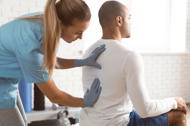 Fisioterapeuta femenino comprobando la espalda del hombre