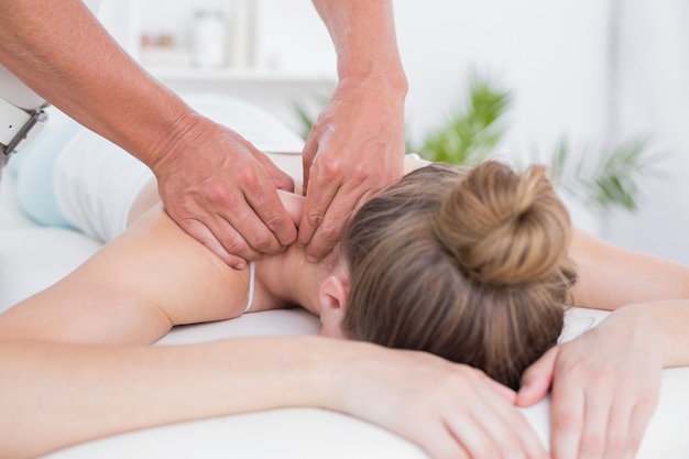 Fisioterapeuta haciendo masaje de brazo a su paciente en consultorio médico