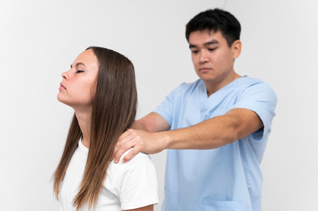 Foto fisioterapeuta masajeando los hombros del paciente femenino