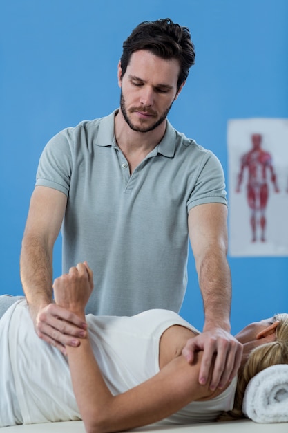 Fisioterapeuta masculino dando masaje de brazo a paciente femenino