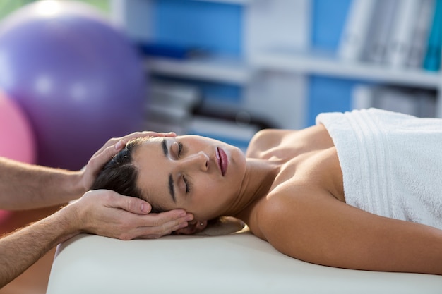 Fisioterapeuta masculino dando masaje de cabeza a paciente femenino