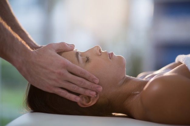 Fisioterapeuta masculino dando masaje de cabeza a paciente femenino