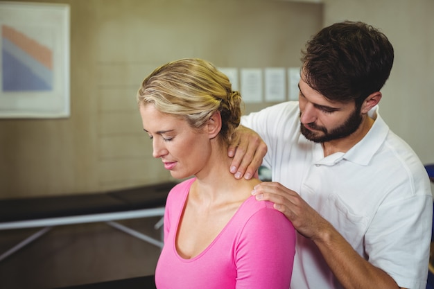 Fisioterapeuta masculino dando masaje de cuello a paciente femenino