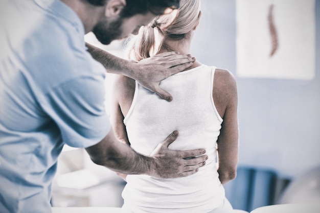 Foto fisioterapeuta masculino dando masaje de espalda al paciente femenino