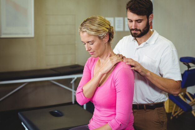 Fisioterapeuta masculino dando masaje de espalda a paciente femenino
