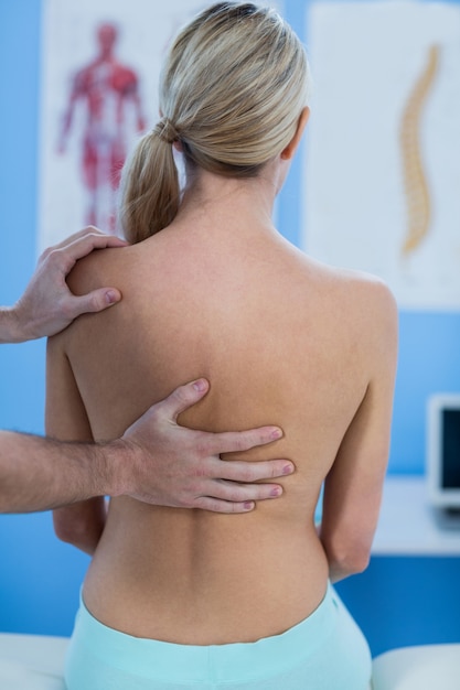 Foto fisioterapeuta masculino dando masaje de espalda a paciente femenino