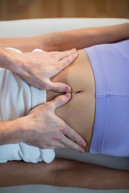 Foto fisioterapeuta masculino dando masaje de estómago a paciente femenino