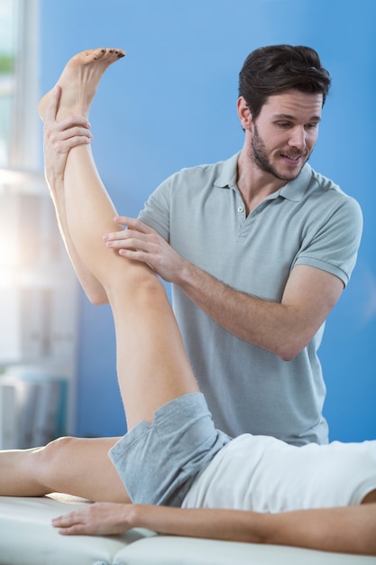 Fisioterapeuta masculino dando masaje de rodilla a paciente femenino