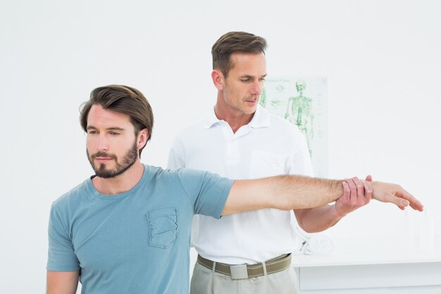 Fisioterapeuta masculino estirando una mano joven mans