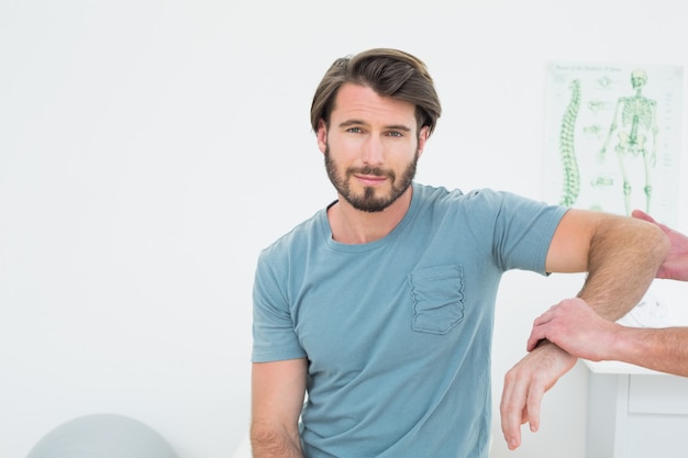 Fisioterapeuta masculino examinando un brazo de hombre joven