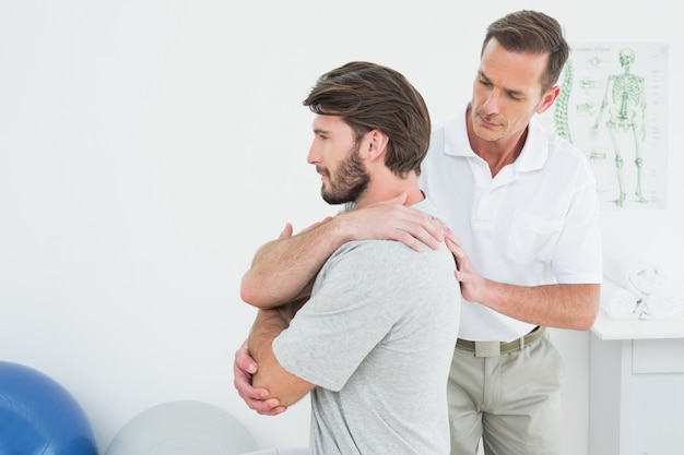 Fisioterapeuta masculino examinando um jovem