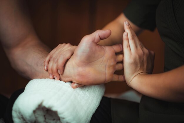 Fisioterapeuta massageando paciente do sexo masculino com lesão muscular na mão Tratamento de lesões esportivas