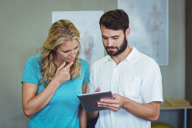 Fisioterapeuta mostrando tableta digital para mujer