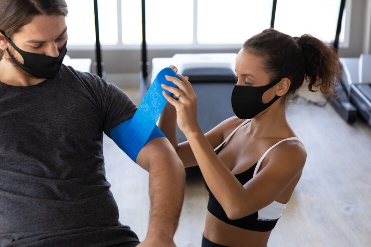 Foto fisioterapeuta mujer hispana aplicar vendaje neuromuscular a su paciente en la clínica profesional de formación de gimnasio.