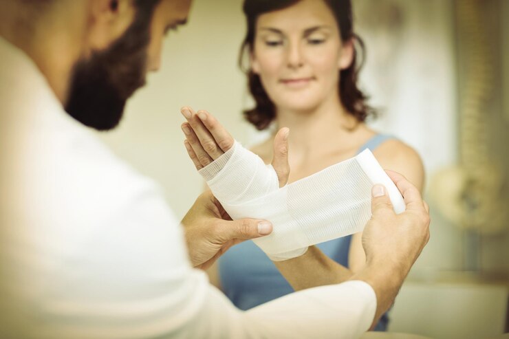 Foto fisioterapeuta poniendo vendaje en la mano lesionada del paciente