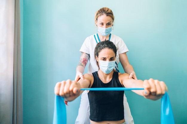 Fisioterapeuta profissional caucasiana em uma clínica fazendo um tratamento de alongamento de pilates com um elástico