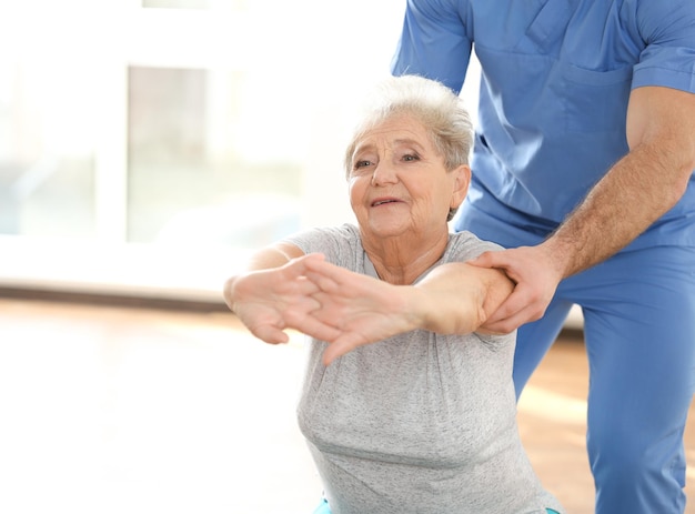 Foto fisioterapeuta que trabaja con el paciente anciano en la clínica