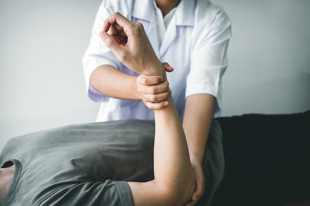 Fisioterapeuta que trata el brazo herido de un hombre