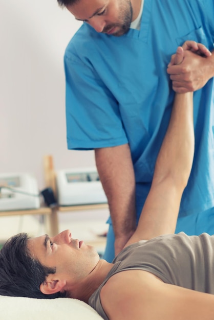 Foto fisioterapeuta trabalhando com o braço do paciente