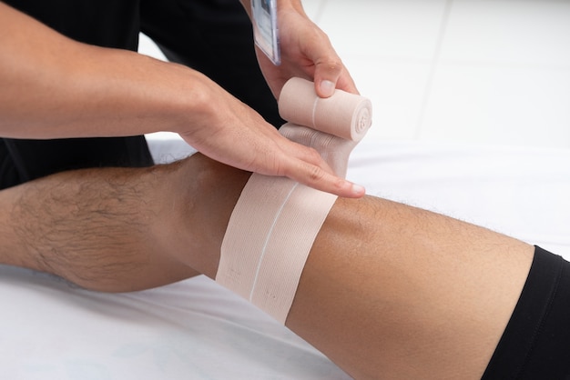 Los fisioterapeutas utilizan las asas en la pierna del paciente para acostarse en la cama en una sala médica.