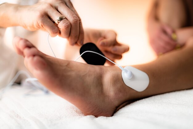 Foto fisioterapia de la articulación del tobillo con almohadillas de electrodos tens estimulación eléctrica transcutánea del nervio