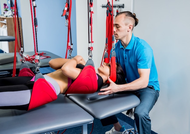 Fisioterapia. Terapia de treinamento em suspensão. Jovem mulher fazendo tração fitness