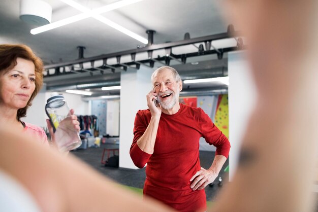 Foto fit älterer mann mit smartphone im fitnessstudio