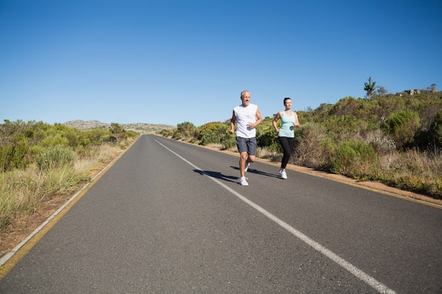 Fit couple correndo juntos na estrada aberta