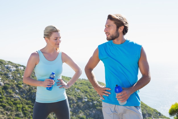 Fit couple standing sosteniendo botellas de agua