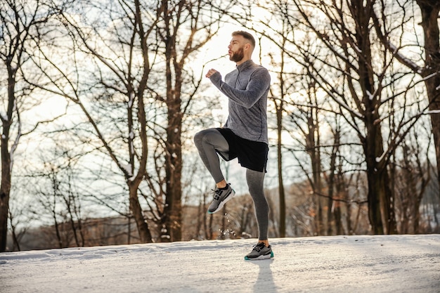 Fit deportista corriendo en la naturaleza en un día nevado de invierno. Clima frío, fitness de invierno, ejercicios cardiovasculares