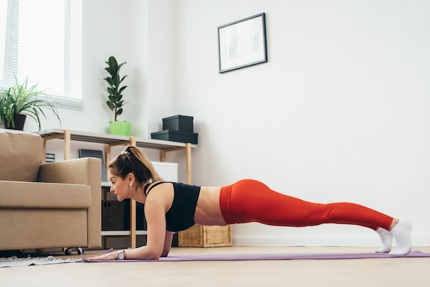 Fit Frau, die Plankenübung zu Hause macht.