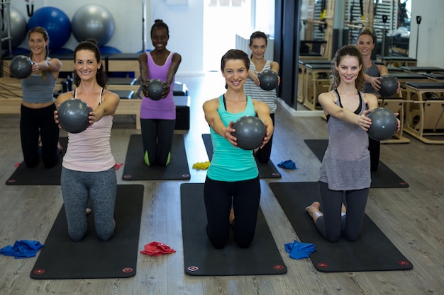 Fit Frauen, die Dehnungsübung mit Fitnessball im Fitnessstudio durchführen