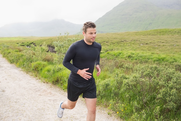 Fit hombre corriendo por un sendero