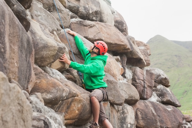 Fit hombre escalando una gran roca