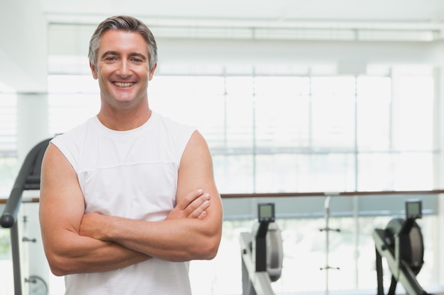 Fit hombre sonriendo a la cámara en el gimnasio