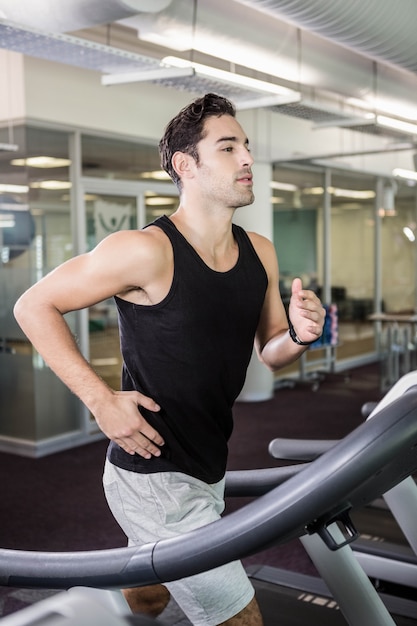 Fit homem correndo na esteira na academia