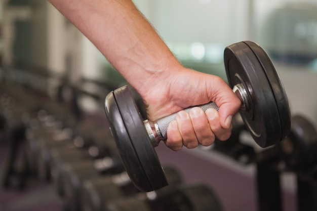 Fit homem levantando pesado dumbbell preto