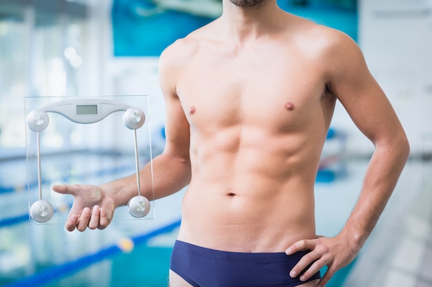 Foto fit homem segurando uma balança de pesagem na piscina