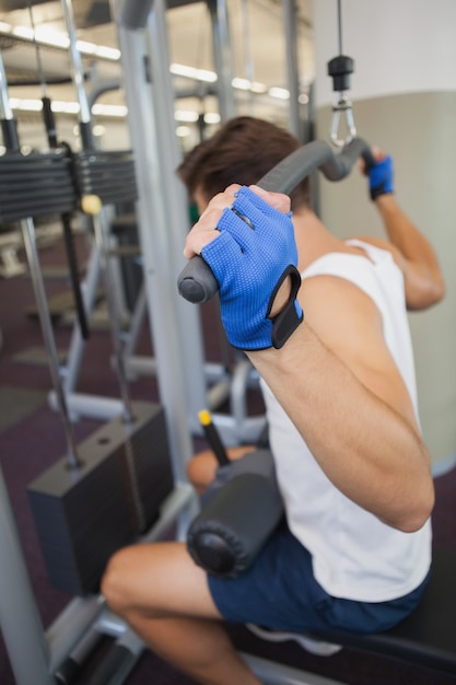 Fit homem usando pesos máquina para armas