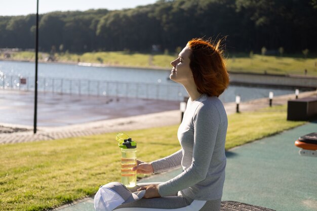 Fit Ingwer Frau in Sportkleidung Trinkwasser beim Training auf dem Sportplatz im sonnigen Herbsttag