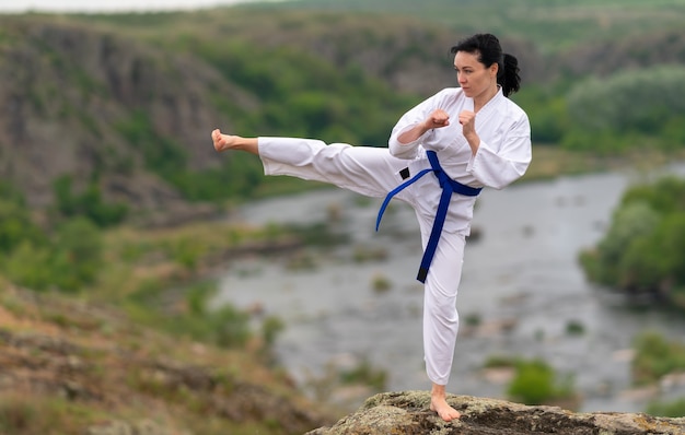 Fit junge Frau Training im Kickboxen im Freien auf einem Felsen