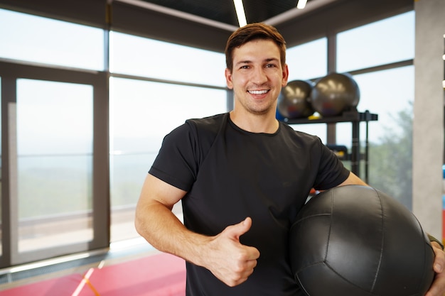 Fit junger Mann, der mit Fitnessball in einem Fitnessstudio trainiert