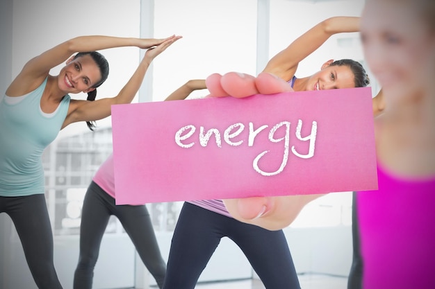 Foto fit loira segurando o cartão dizendo energia contra a aula de fitness no ginásio