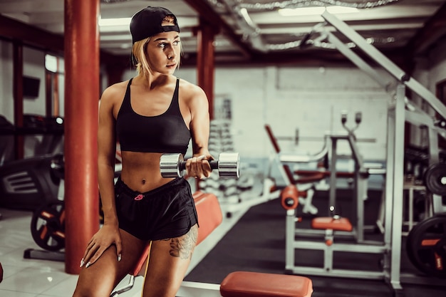 Fit Mädchen Übung mit Hanteln im Fitnessstudio.