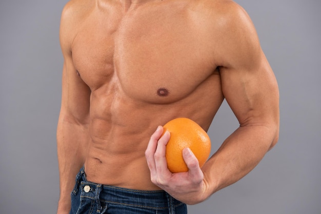 Fit man beschnittene Ansicht mit Sixpack-Muskeltorso halten Orangenfrüchte als Diätsymbol, Vitamin C. Männer Gesundheit.